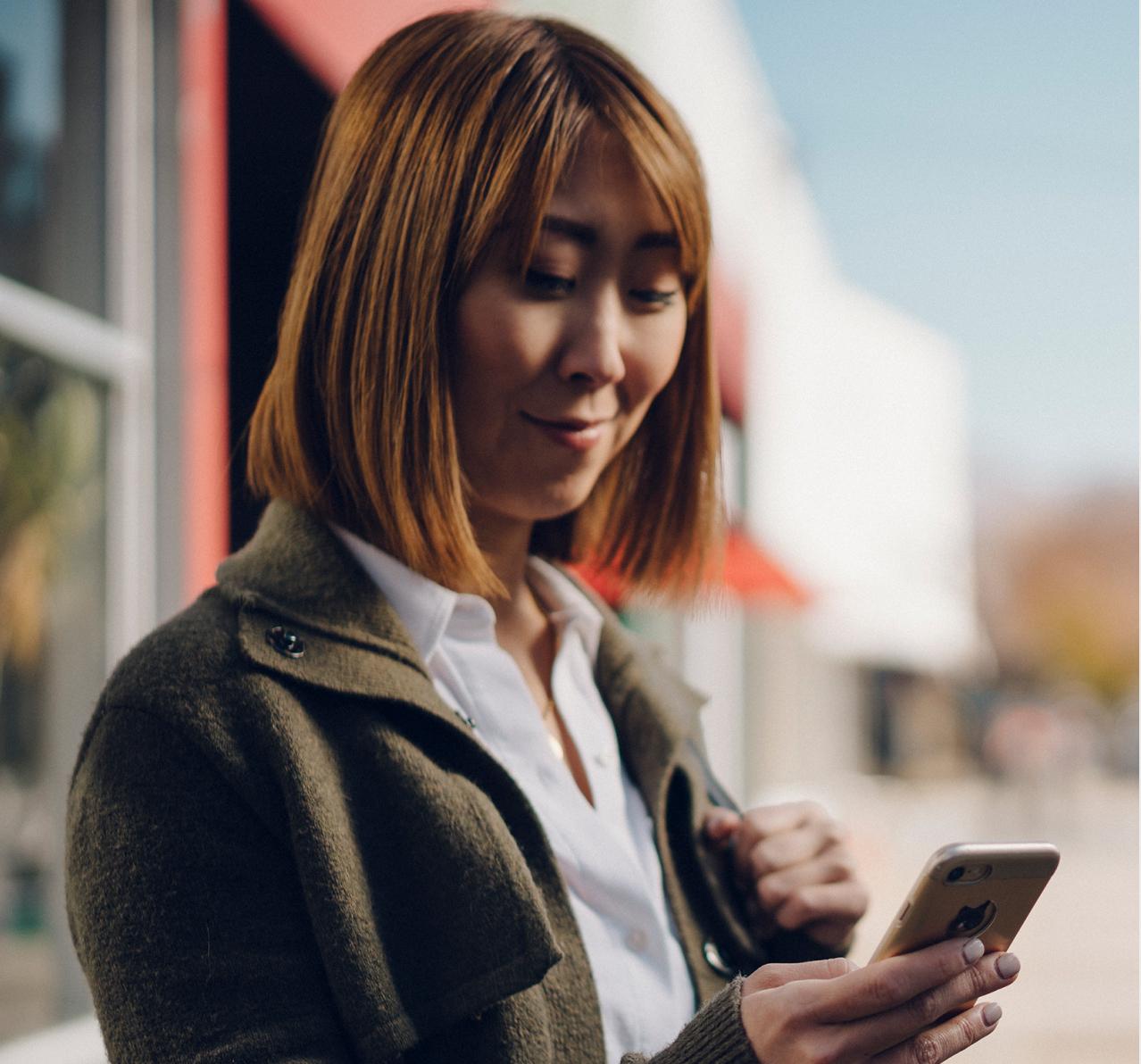 Woman texting outside of a business